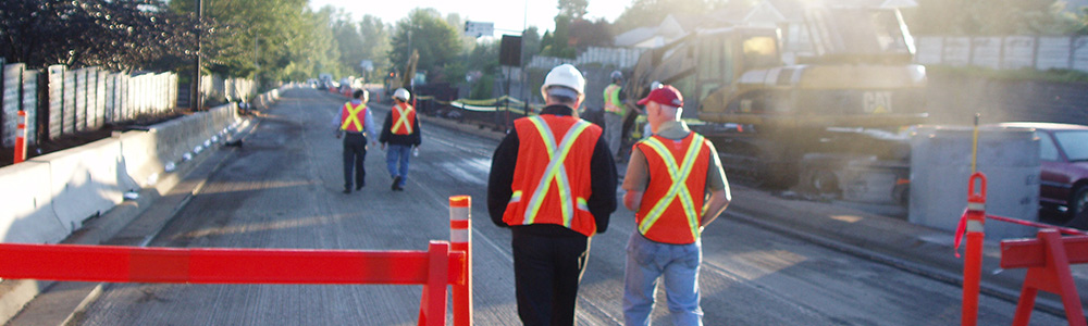 Construction site staff walking along roadway