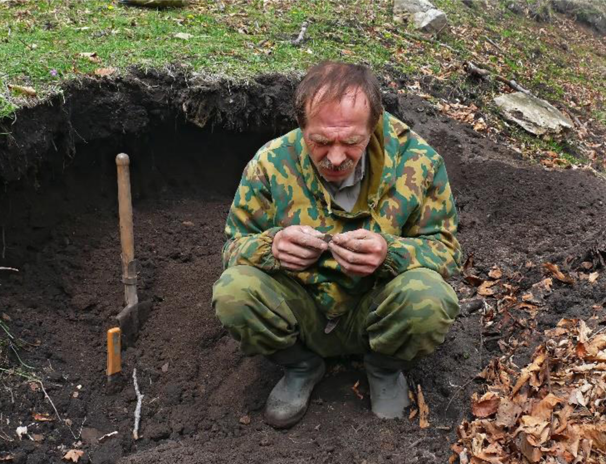 Figure 6 – Man examining a discovered object inside an excavation