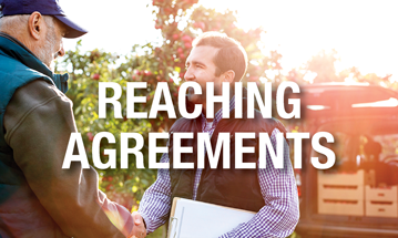 Man with clipboard shaking hands in agreement with man on his rural land