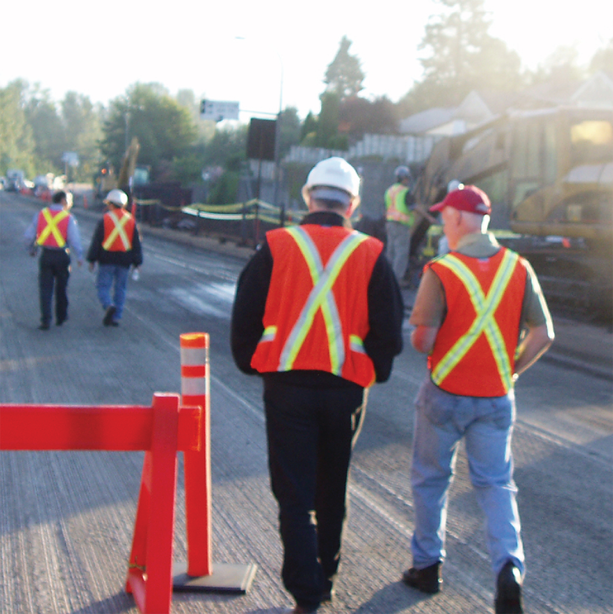 Travailleurs de la construction portant des gilets réflecteurs marchant sur une route nivelée