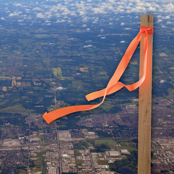 A surveyor’s stake is superimposed over an aerial photo of farmland