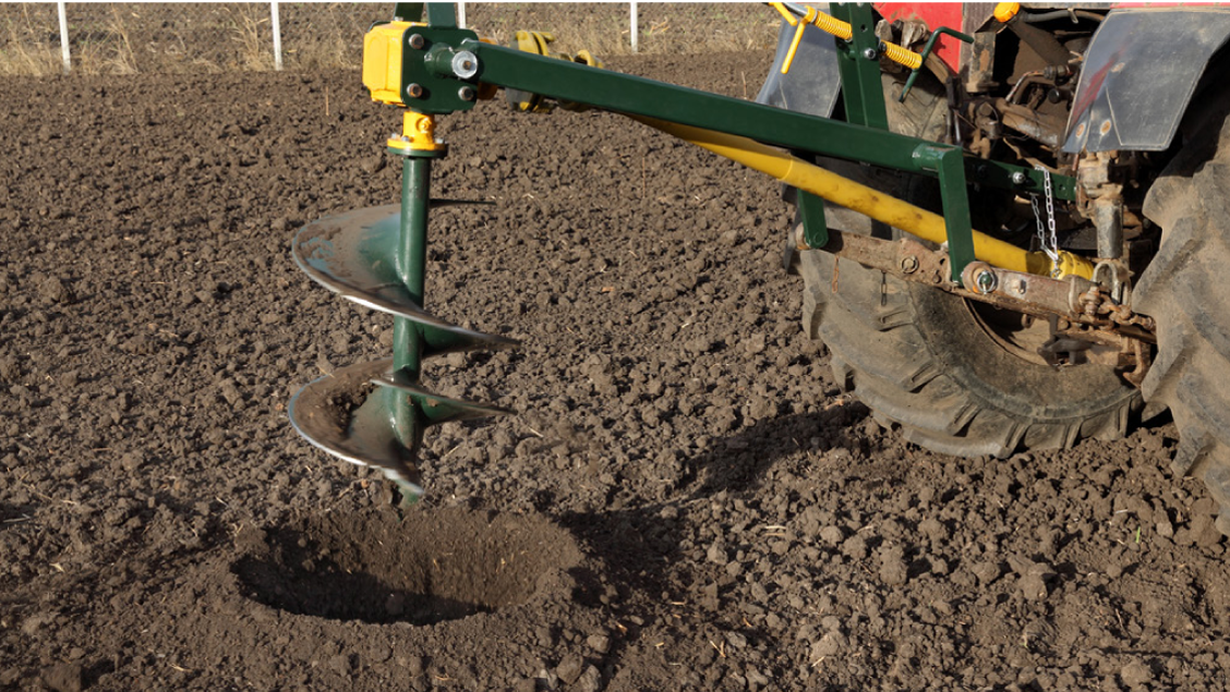 A power auger digs a hole
