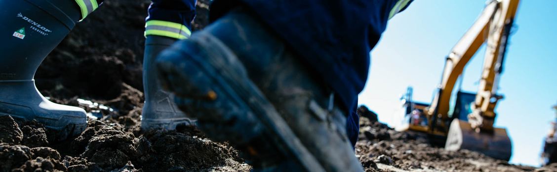 Bottes de travail au premier plan et chantier en arrière-plan