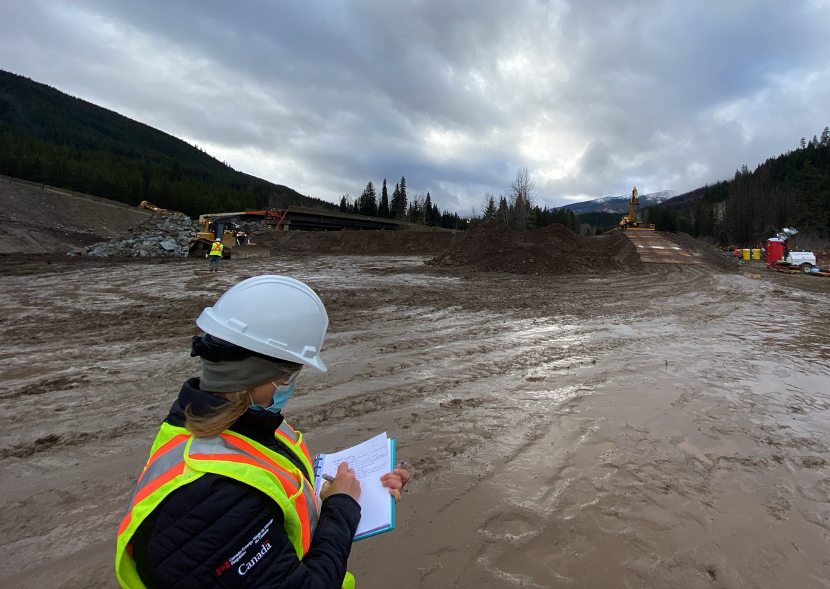 An environmental protection inspection officer oversees installation of a temporary bridge by Trans Mountain.
