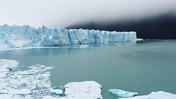 A wall of ice stands in the background as sheets of ice float in the foreground in a bay in Canada’s north.