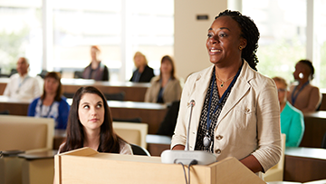 A woman stands at a podium to address a hearing.