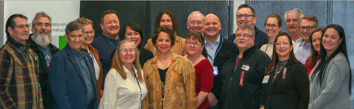Employés de la Régie et membres de communautés autochtones debout devant une affiche sur laquelle est inscrite « Régie de l’énergie du Canada »