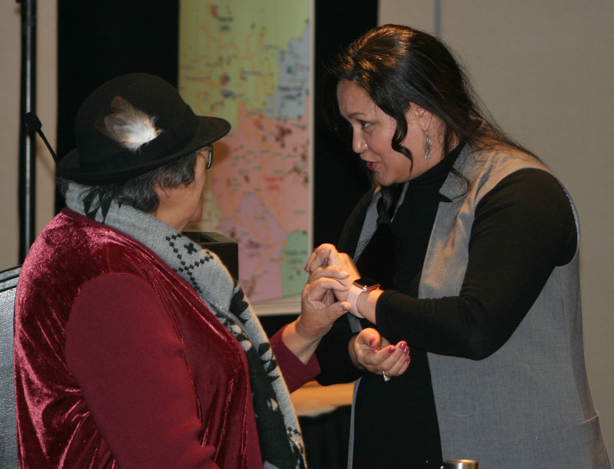 Michelle Wilsdon, spécialiste en chef de la Réconciliation, tenant la main de l’Aînée Irene Morin de la Nation crie d’Enoch, qui porte un chapeau avec une plume 