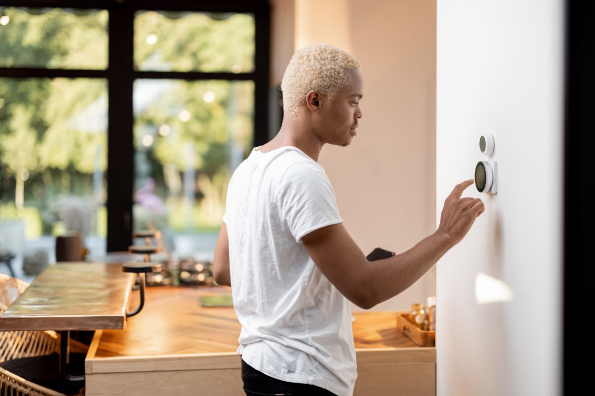 Homme utilisant un compteur d’énergie intelligent à la maison avec un téléphone intelligent à la main.