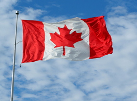 Maple leaves The Canadian flag flutters against a partially cloudy sky