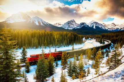 A transport train weaves through the Rockies on a winter day