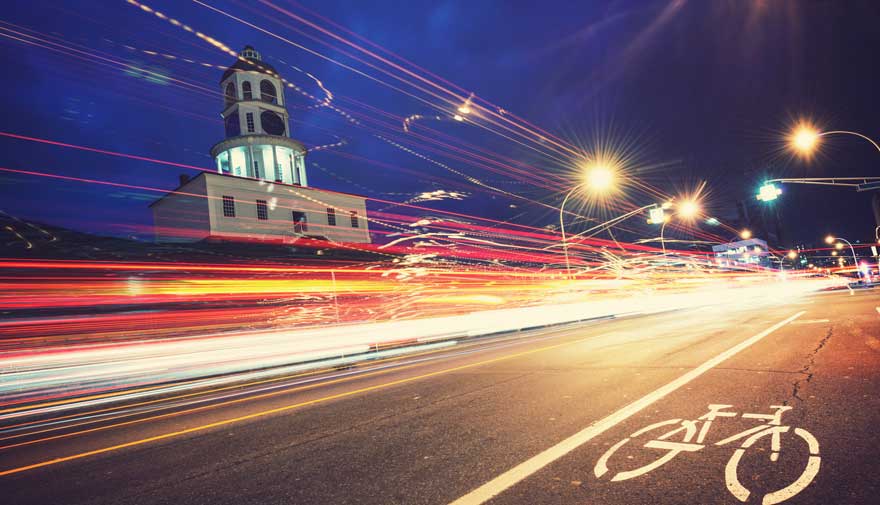 Blurred nighttime traffic lights illuminate a bike lane in downtown Halifax