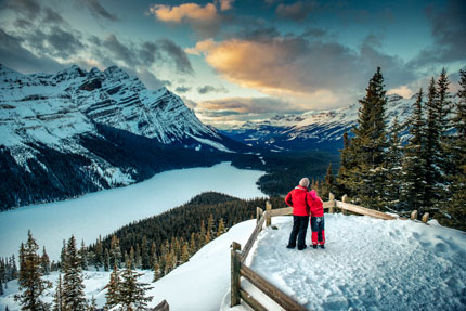 A mother and daughter enjoying the view of frozen mountain lakes in winter