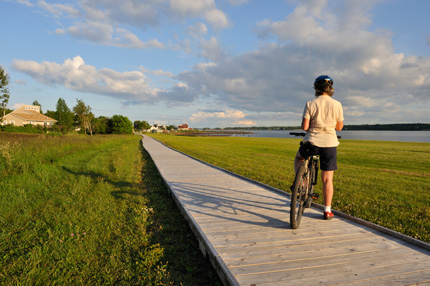 Femme à vélo sur un long trottoir de bois à la brunante