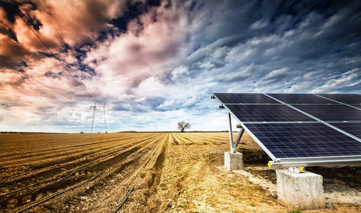 Solar energy panels on a field under dramatic sky