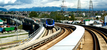 Vancouver light rail train traveling over a bridge in an industrial park.