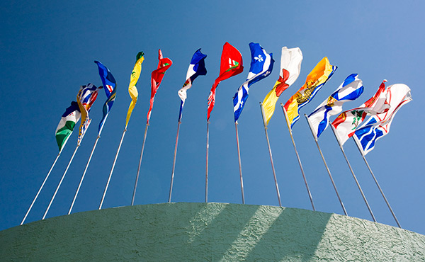 The provincial flags, as seen from below, arranged in a semicircle on top of a wall.