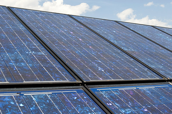 A close up of a group of solar panels on a cloudy summer day.