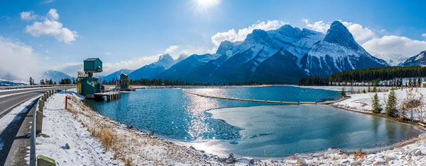 Hydro power station at snowy lake in Canmore, with mountain in the background.