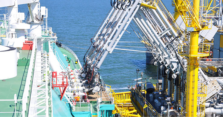 A liquefied natural gas tanker unloading cargo with a multi-handed crane to a terminal pipeline