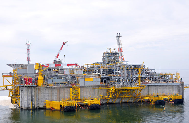 A liquid natural gas offshore terminal floating off the coast on a cloudy day.