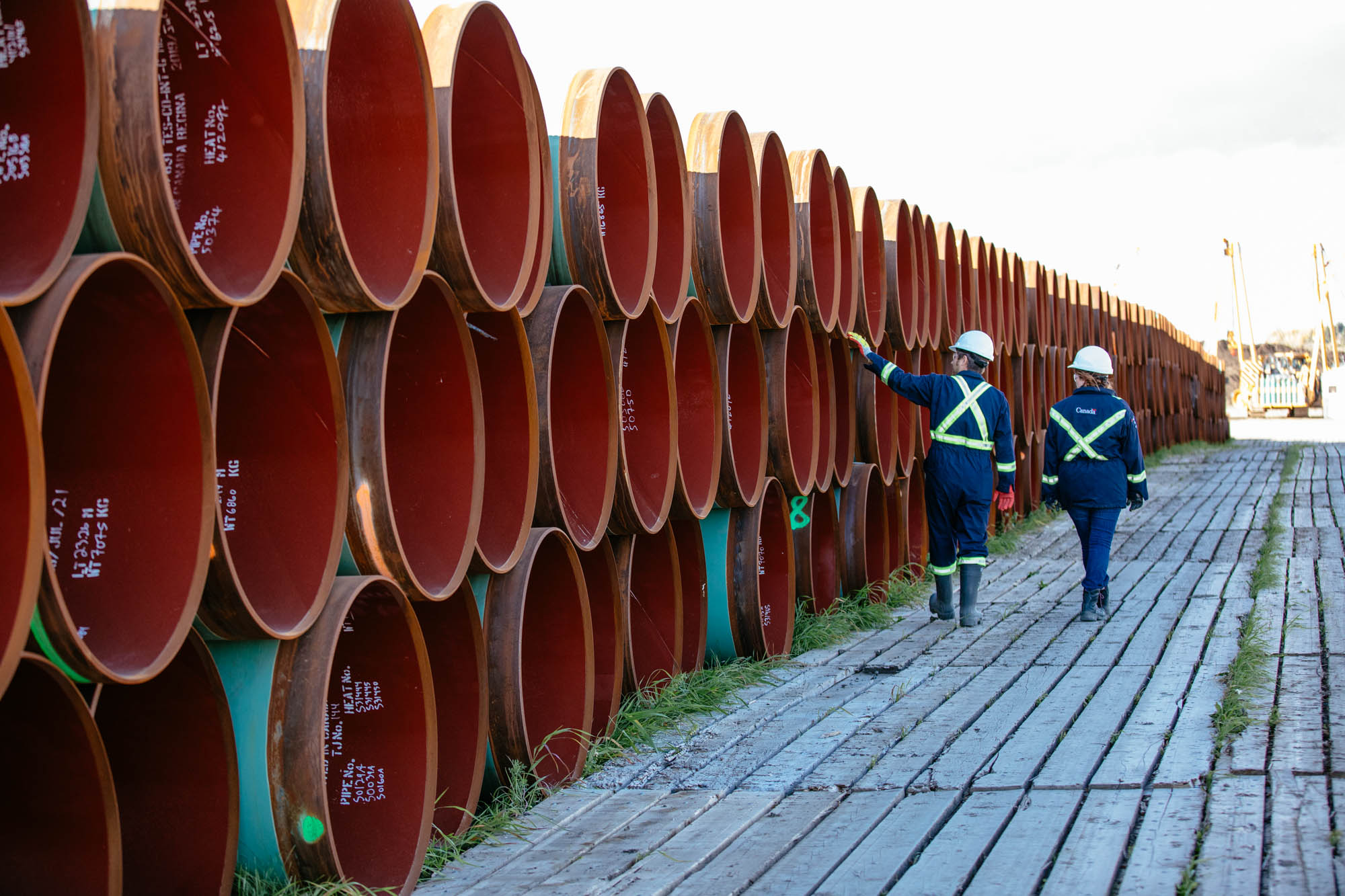 Two CER inspection officers examining rows of pipes to be installed.