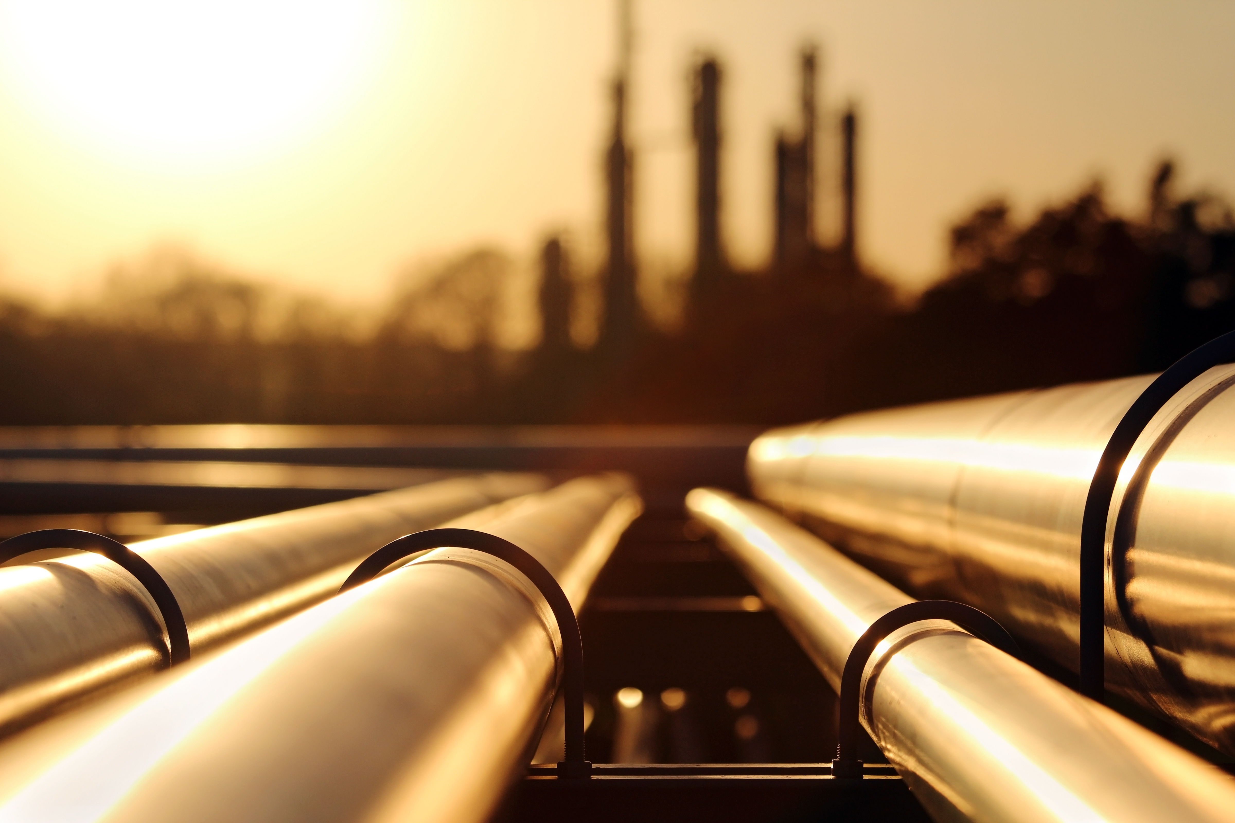 Pipes in foreground, with blurry refinery in the background.