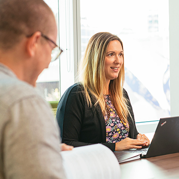 Two CER employees at meeting with printed reports and laptop, sharing information