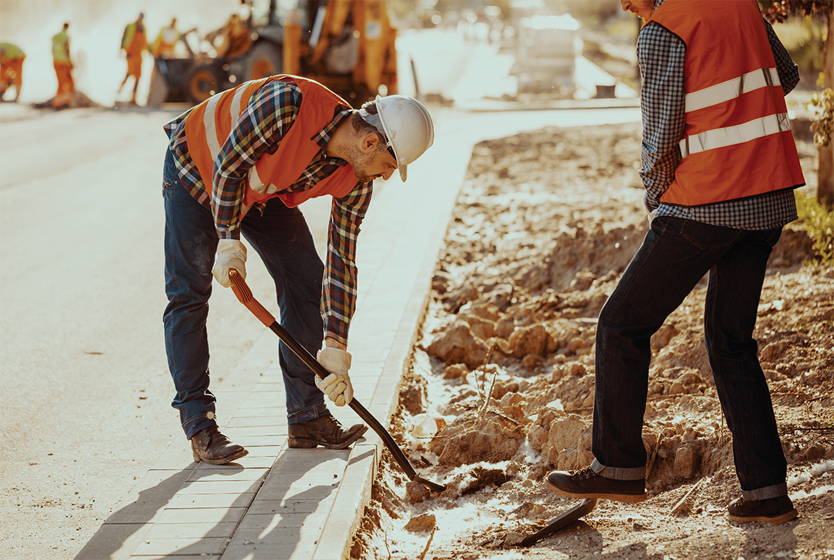 Travailleurs en gilets réflecteurs utilisant des pelles pour effectuer des travaux sur la chaussée