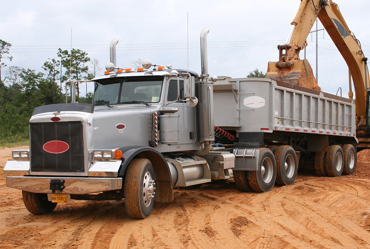 Grue chargeant un camion à benne sur un terrain dégagé