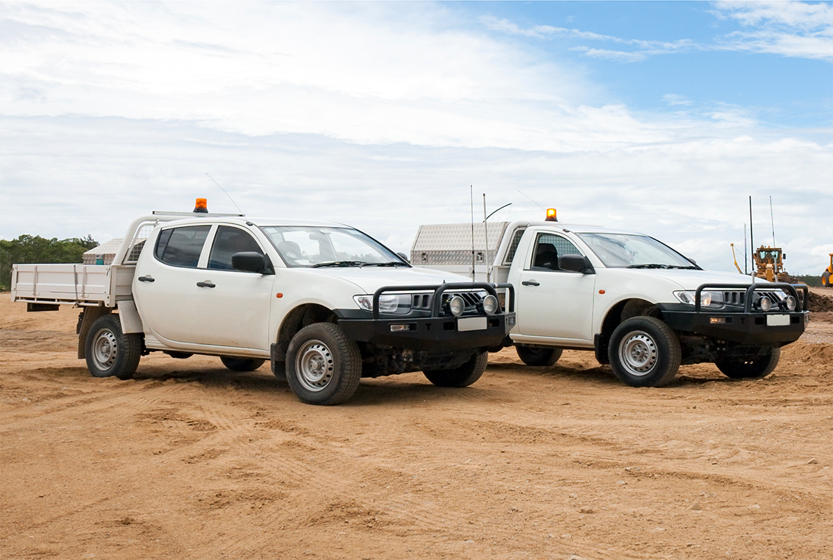 Deux camions blancs stationnés sur un terrain dégagé