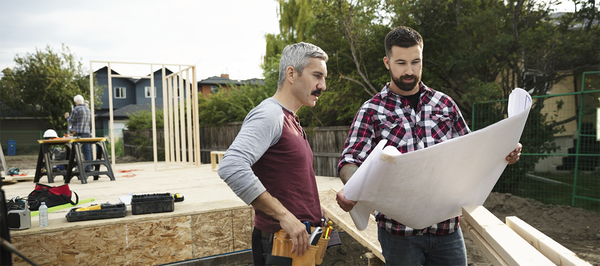 Deux hommes examinant des plans sur un chantier de construction