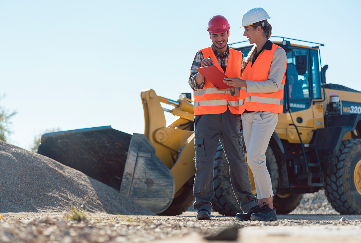 Deux travailleurs de la construction, un homme et une femme, discutent d’un nouveau projet sur un chantier