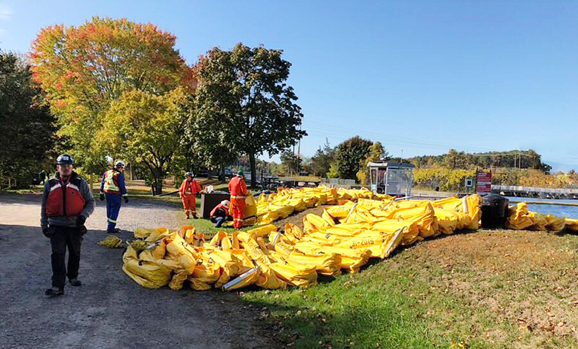 Company staff at the side of a river working to put a boom into the water for an emergency exercise.