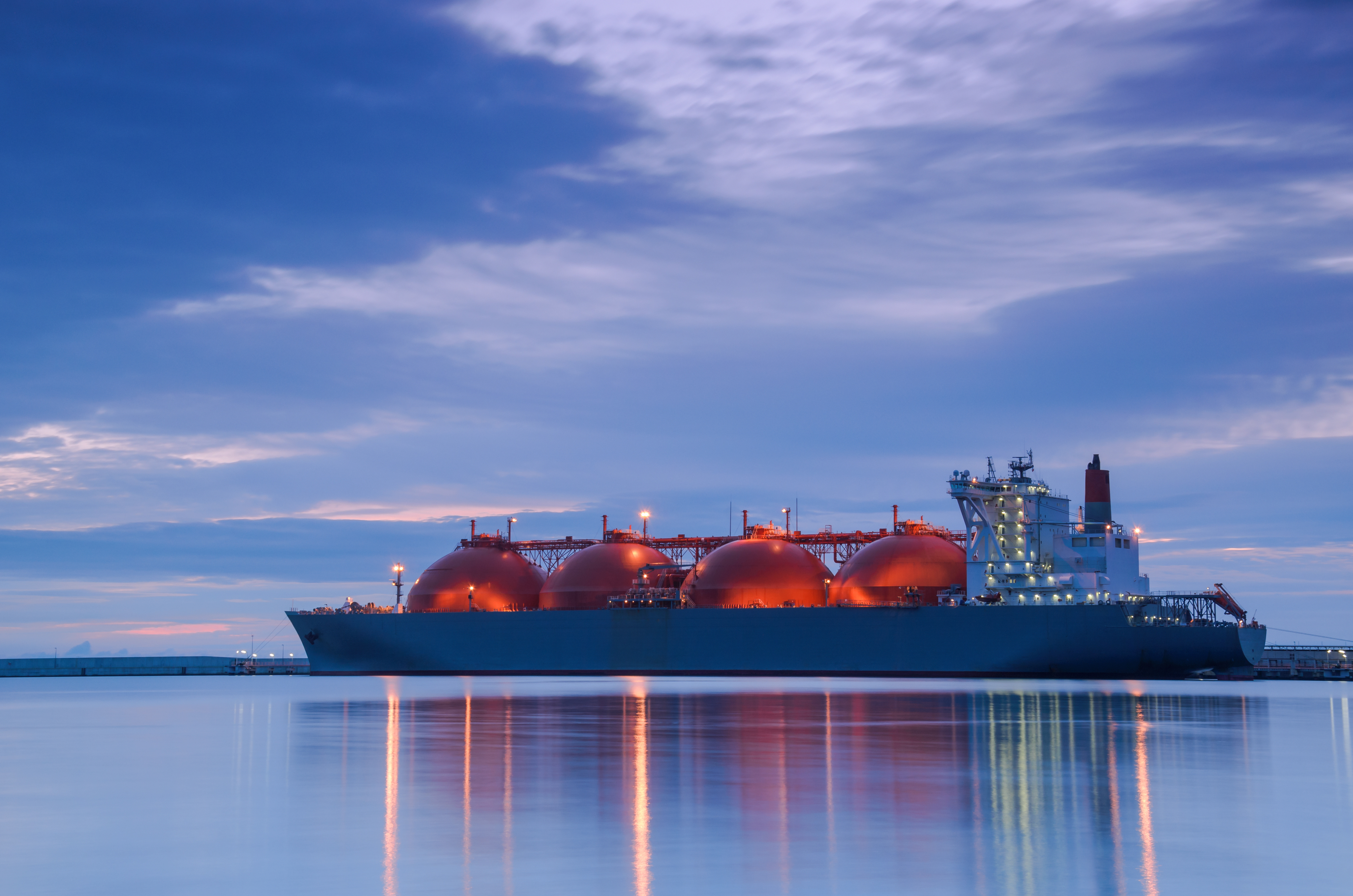 Un méthanier navigue sur des eaux calmes au crépuscule.